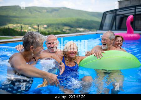 Senior Pool Fun Group of cheerful seniors shaving fun in pool jumping, swiming and ...
