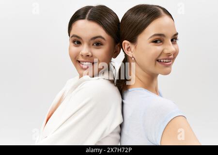 Two pretty brunette teenage girls in sportive attire standing side by side in a studio setting. Stock Photo