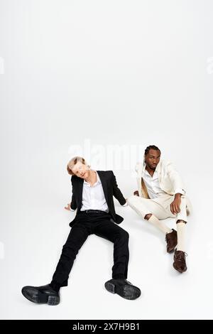 Two multicultural men in elegant suits sitting closely, engaged in conversation. Stock Photo