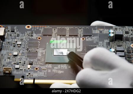 The technician is adding cooling silicone. Graphics motherboards and graphics card repairs, computer parts Stock Photo
