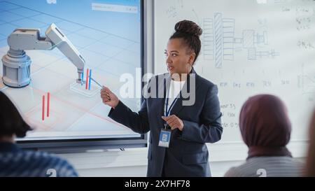 Teacher Giving a Lesson to Diverse Students and Pointing at Robotic Hand, Fluctuations of Data in Charts on Interactive Whiteboard in University Classroom. Robotic Engineering Education Concept. Stock Photo