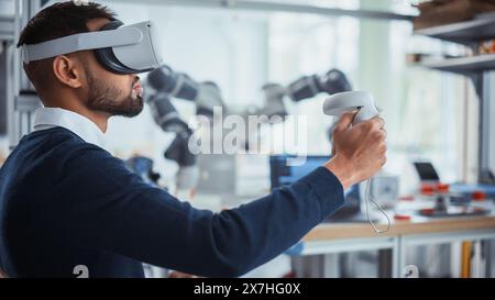 Computer Science Worker in Virtual Reality Headset Holding Controllers and Moving Bionic Claw. Man Developing Program for Motion of Robotic Arm. Innovative Automation Technologies Concept. Stock Photo