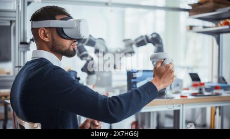 Computer Science Worker in Virtual Reality Headset Holding Controllers and Moving Bionic Claw. Man Developing Program for Motion of Robotic Arm. Innovative Technologies for Automation Concept. Stock Photo
