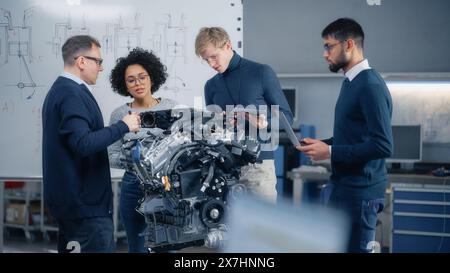 Team Meeting of Engineers Working on Innovative Electric Motor. Group of Specialists Gathered Around Table, Solving Problems. Research, Development, Digitalisation of Green Electric Energy Concept. Stock Photo
