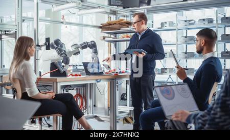 Busy Diverse Team of Computer Engineers and Specialists Gather in the Factory Meeting Room, They Discuss New Project, Looking for Problem Solutions Together. Development and Robotics Concept. Stock Photo