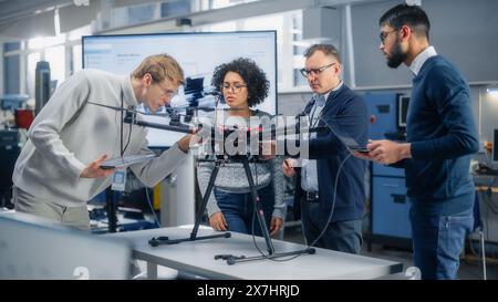 Team of Aviation Engineers Work on a New Drone, Have Discussion, Use Laptop In the Scientific Laboratory. Diverse Scientists Talking and Examining. Startup and Innovations Concept. Stock Photo