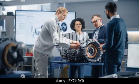 Team Meeting of Engineers: Working on Innovative Electric Motor. Group of Specialists Gathering Around Table, Solving Problems. Research, Development, Digitalisation of Green Electric Energy Concept. Stock Photo
