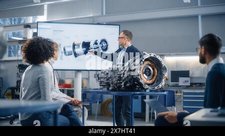 Group of Young Scientists Working: Inspecting Engine in Factory Meeting Room. People Brainstorming with Chief Engineer. Confident Industrial Specialists in Technological Facility. Stock Photo