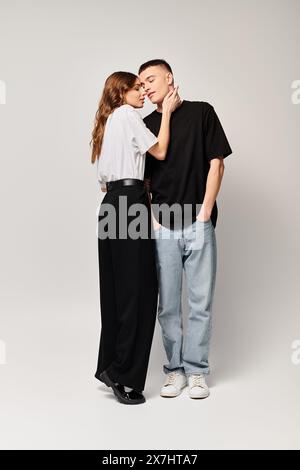 A young couple in love standing side by side in a studio against a grey background. Stock Photo