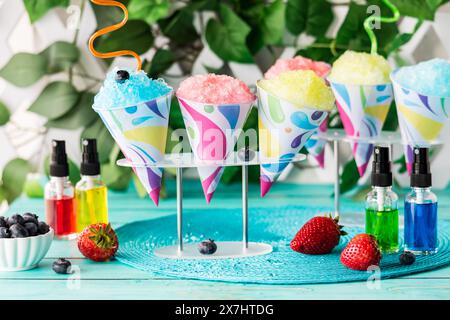 Colourful flavoured snow cones with fruit flavoured syrups in front. Stock Photo