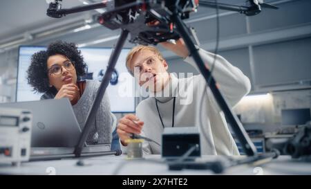 Male Engineer Puts Processor in the Drone While Female Developer Programming on Laptop Computer. Futuristic and Innovative Technologies for Unmanned Aerial Vehicle Concept. Stock Photo
