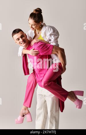 A stylish young man tenderly holds a woman in his arms against a grey studio background. Stock Photo