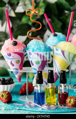 Colourful homemade snow cones with fruit flavoured syrups in front. Stock Photo