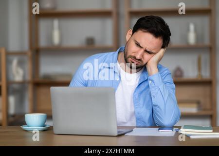 Frustrated Young Man Experiencing Challenges While Working on Laptop Stock Photo