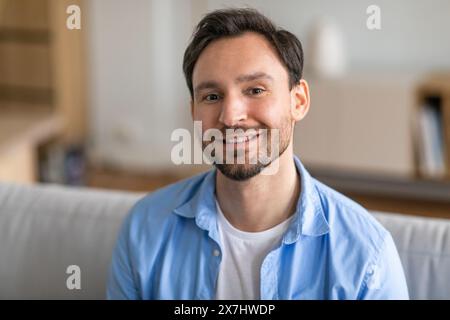 Handsome Bearded Man Smiling on Couch at Home Stock Photo