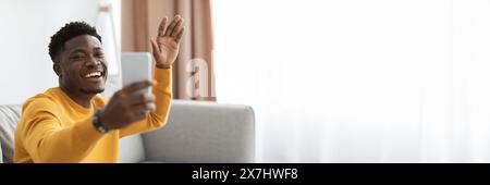 Cheery black man having online party with friends, using smartphone Stock Photo
