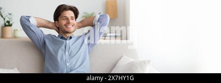 Relaxed young man sitting on couch at home Stock Photo