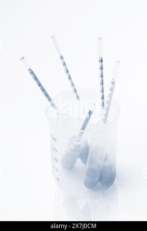 Several old glass float hydrometers in empty plastic chemical beaker Stock Photo