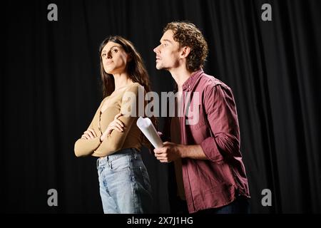 A man and a woman striking a pose in front of a black background. Stock Photo