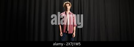 A man standing confidently in front of a black curtain. Stock Photo