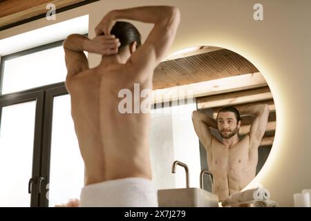 A man with a towel preparing for the day, with a mirror. Stock Photo