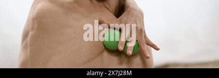 A man peacefully holds a green massage ball in his right hand while practicing yoga at home. Stock Photo