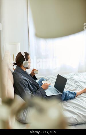 A man and Man sit on a bed with laptops open, focusing on work and communication. Stock Photo