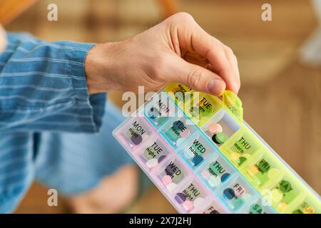 A handsome man at home in the morning, peacefully holding a plastic pill organizer. Stock Photo