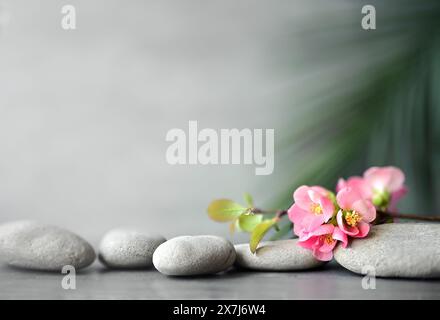 Spa stones with palm branch and flowers on grey background. Spa concept. Stock Photo