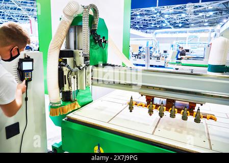 A man works on a CNC milling and engraving machine at the exhibition Stock Photo