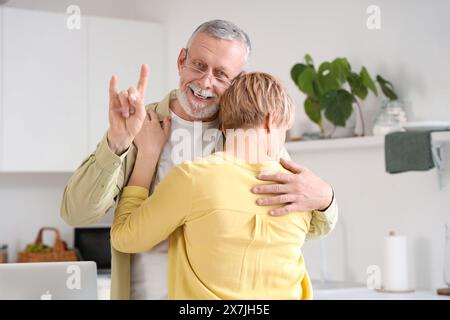 Mature deaf mute man with his wife using sign language in kitchen Stock Photo