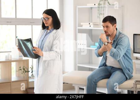 Female doctor with coughing patient studying x-ray image of lungs in clinic Stock Photo