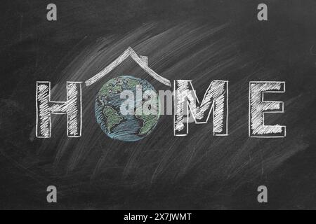 Earth is beautifully drawn in chalk, forming the letter O in the word HOME on a black chalkboard. Roof over the globe. Stock Photo