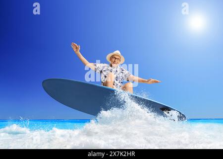 Elderly man riding a surfboard on a wave in the sea Stock Photo