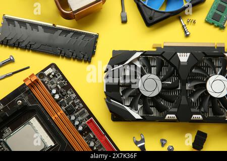Graphics card and other computer hardware on yellow background, flat lay Stock Photo