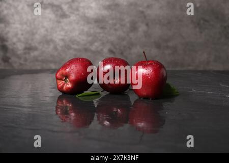 Wet red apples on dark grey table Stock Photo