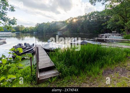 Boats are  lined up along the shore as the sun dips behind the trees on a northwoods Wisconsin lake. Stock Photo