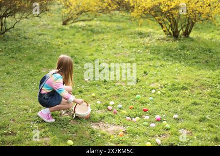 Easter celebration. Cute little girl hunting eggs outdoors Stock Photo