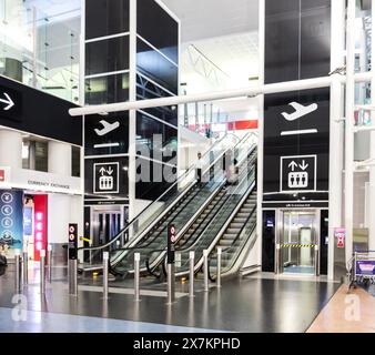 Auckland, New Zealand - February 21, 2024: Travelers using the escalator inside Auckland International Airport. Stock Photo