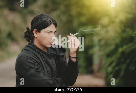 Portrait of handsome guy smoking outdoors. Young man smoking cigarette on the street Stock Photo