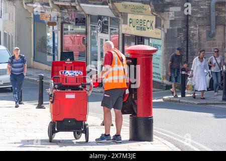 Royal Mail postman emptying a post box, High Street, Swanage, Isle of Purbeck, Dorset, England, United Kingdom Stock Photo