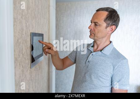 Man using tablet panel application for control smart home living. Wireless device controller for home automation IoT on the wall Stock Photo