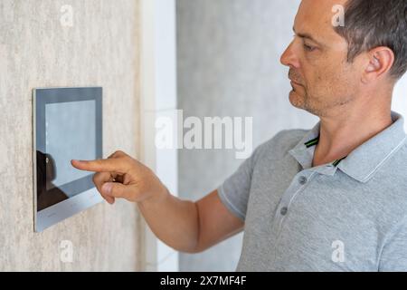 Man using tablet panel application for control smart home living. Wireless device controller for home automation IoT on the wall Stock Photo
