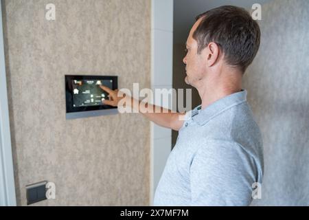 Man using tablet panel application for control smart home living. Wireless device controller for home automation IoT on the wall Stock Photo