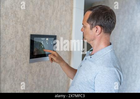 Man using tablet panel application for control smart home living. Wireless device controller for home automation IoT on the wall Stock Photo