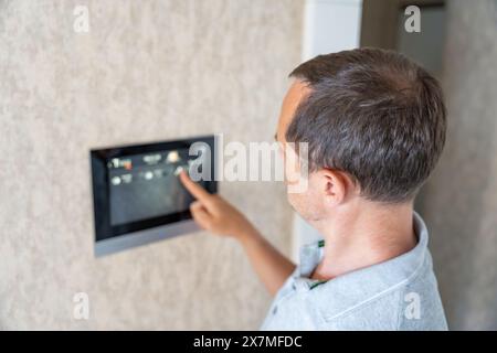 Man using tablet panel application for control smart home living. Wireless device controller for home automation IoT on the wall Stock Photo