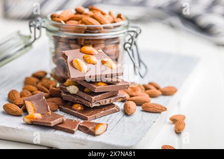 Broken chocolate bar with almonds on a kitchen table. Stock Photo