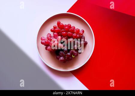 Red grapes with color blocking and geometric shadow aesthetic. Stock Photo