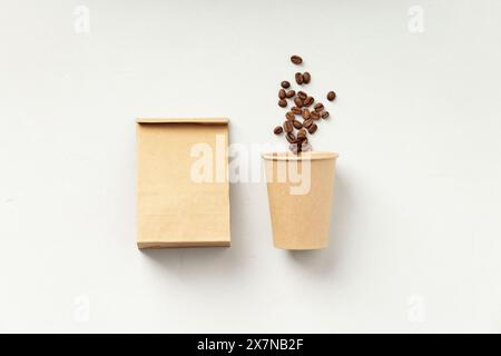 A paper coffee cup beside a brown bag with coffee beans on a white background. Stock Photo