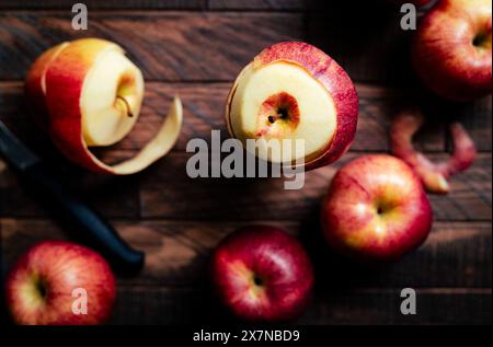 peeling red apples on a wooden surface Stock Photo